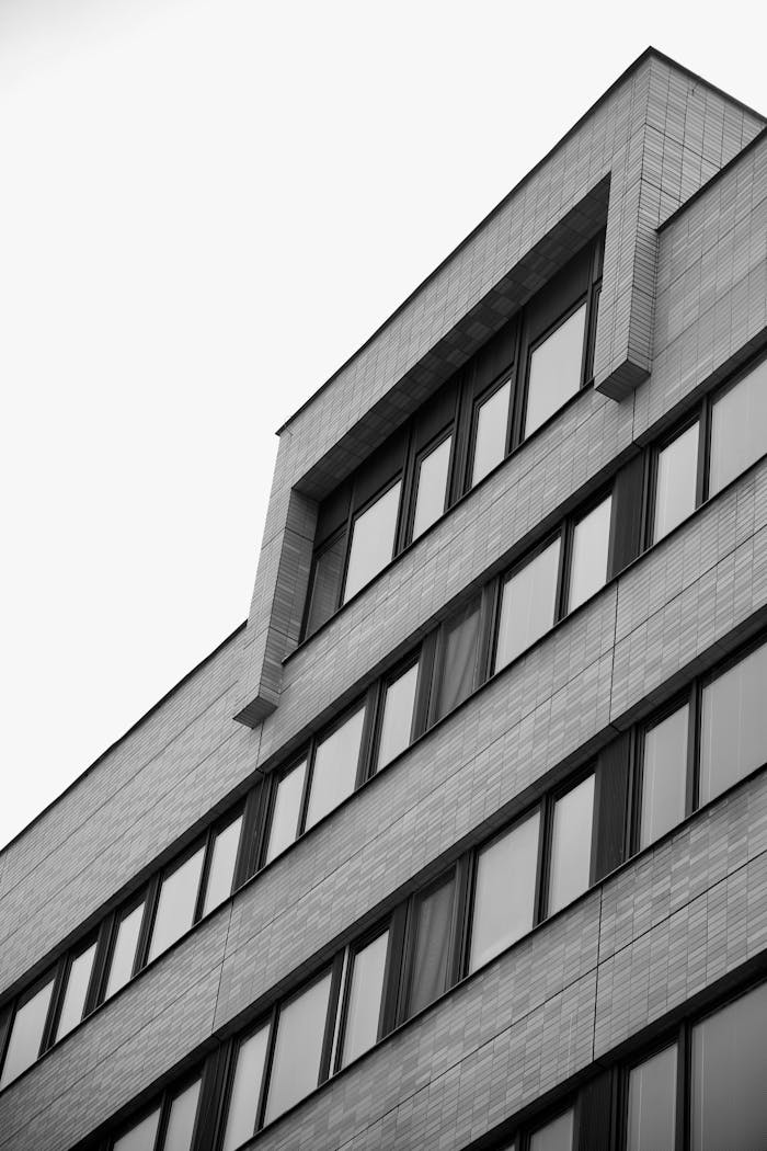 A detailed black and white view of a modern building facade showcasing windows and geometric lines.