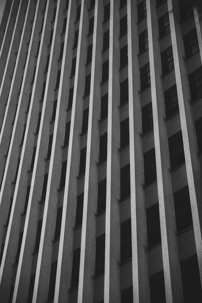 Black and white image of a modern skyscraper facade showing vertical lines and geometric patterns.